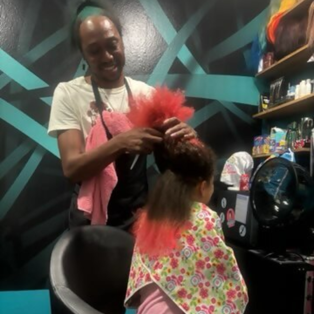 A person styling another's bright red hair in a salon.