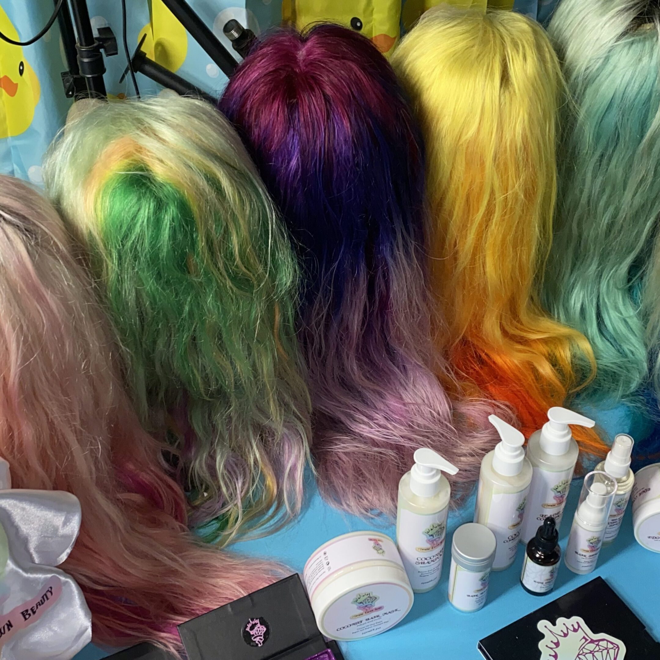 Colorful wigs and hair care products displayed on a table.