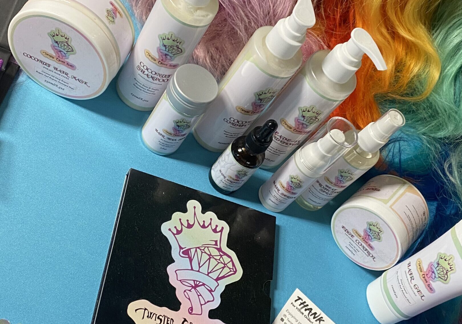 Various hair care products and colorful wigs displayed on a blue surface.
